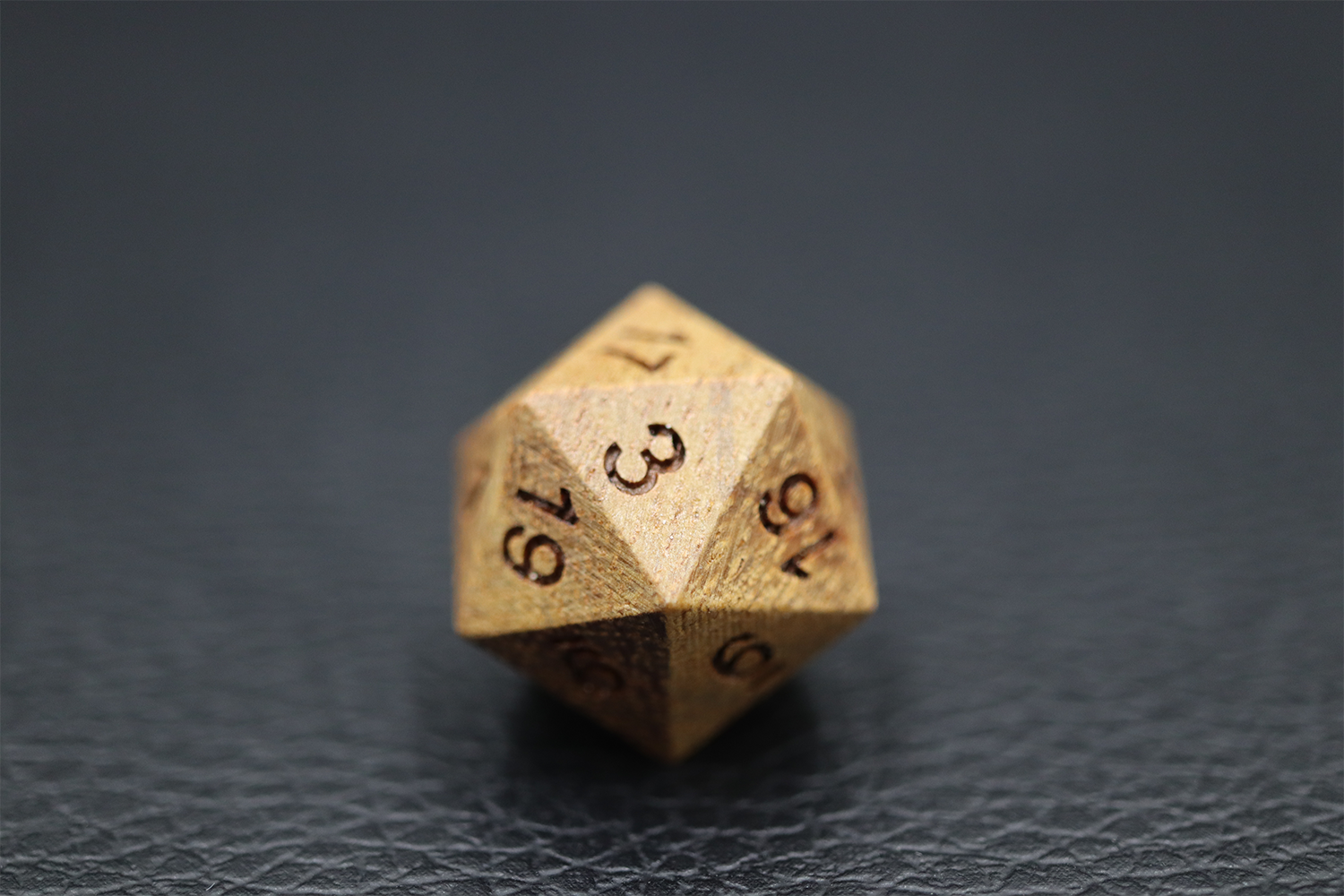 A single gold d20 resting on dark leather